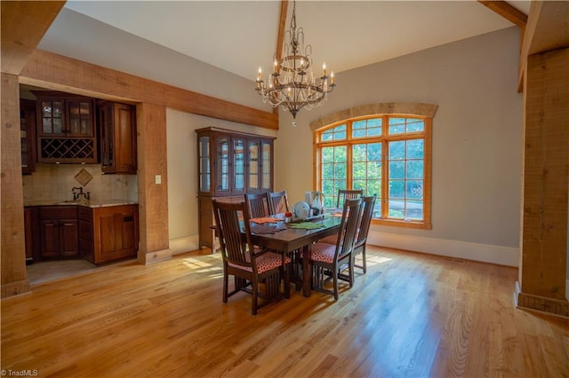 dining area with a notable chandelier, vaulted ceiling, and light hardwood / wood-style floors