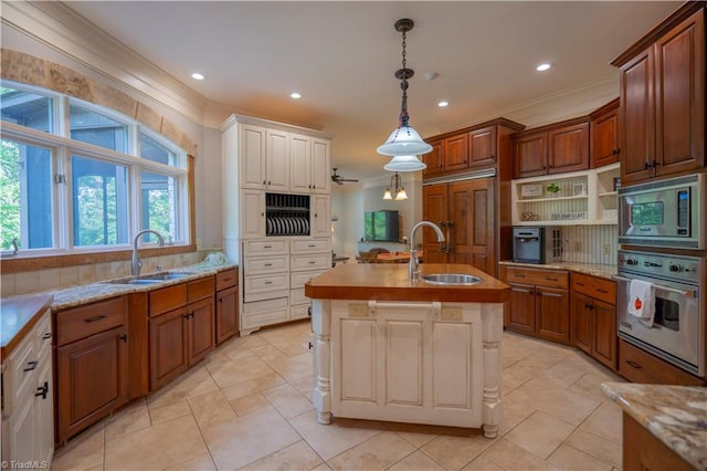 kitchen with crown molding, appliances with stainless steel finishes, sink, and a kitchen island with sink