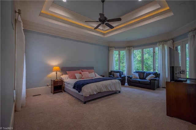 carpeted bedroom with ceiling fan, a raised ceiling, and crown molding