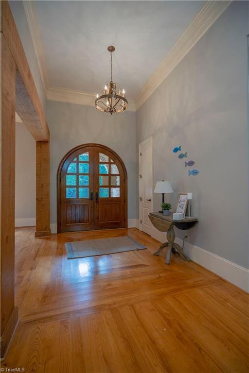 foyer featuring french doors, ornamental molding, light hardwood / wood-style floors, and a chandelier