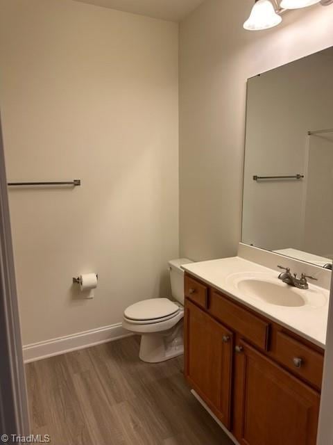 bathroom with vanity, wood finished floors, toilet, and baseboards