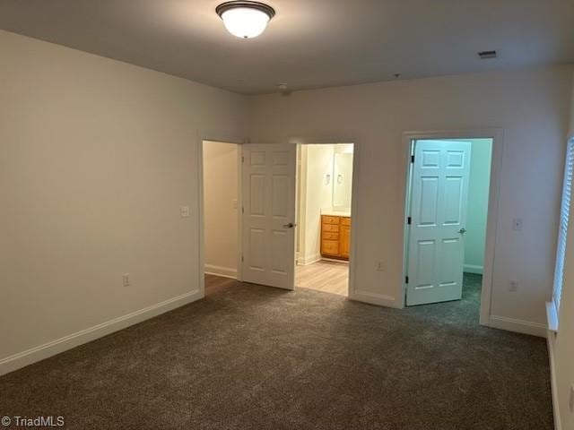 unfurnished bedroom with carpet, visible vents, ensuite bath, and baseboards