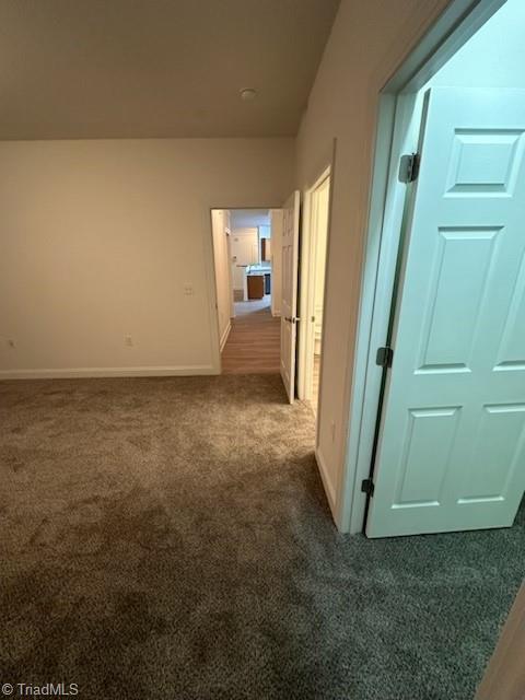 hallway with carpet floors and baseboards