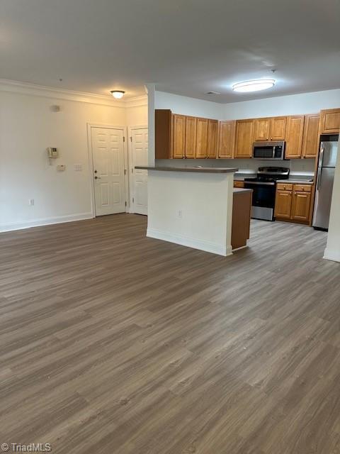 kitchen featuring appliances with stainless steel finishes, brown cabinetry, open floor plan, wood finished floors, and baseboards