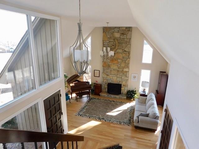 living room with high vaulted ceiling, a fireplace, and light hardwood / wood-style floors