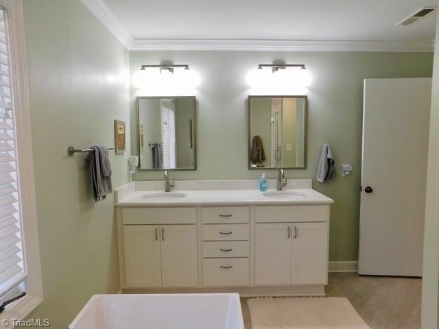 bathroom with ornamental molding, a washtub, and vanity