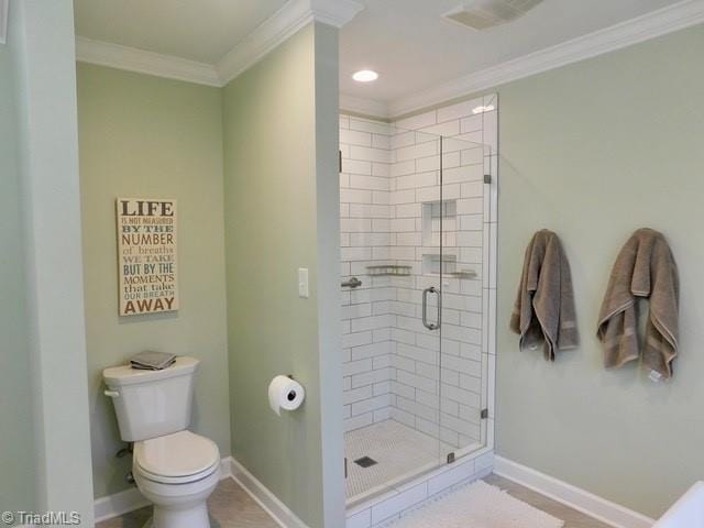 bathroom featuring crown molding, a shower with door, and toilet