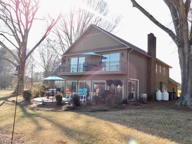 back of house with a balcony, a yard, and a patio