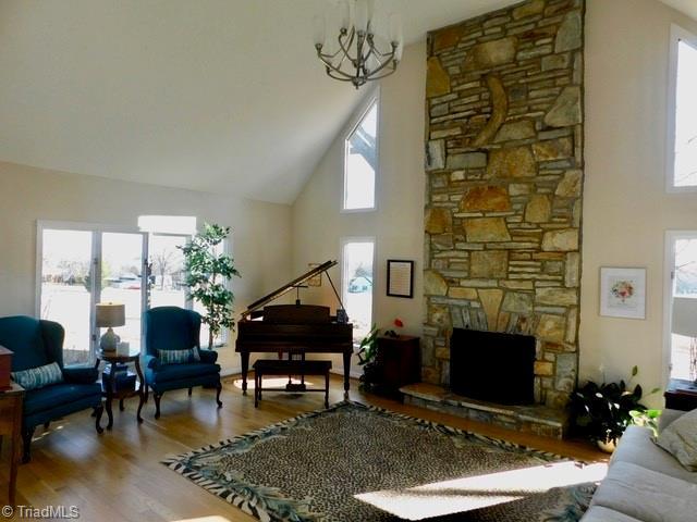 living room with wood-type flooring, a fireplace, high vaulted ceiling, and a wealth of natural light