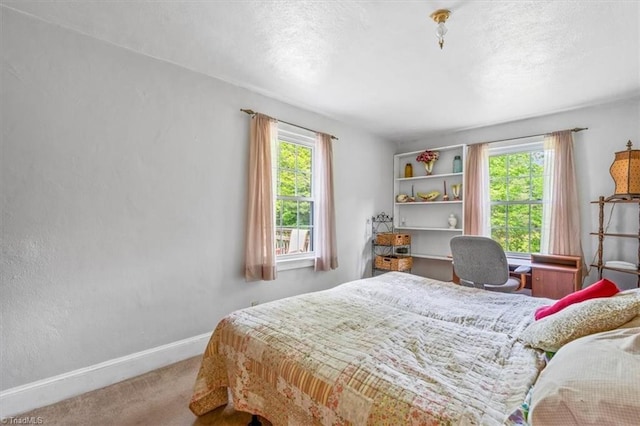 carpeted bedroom featuring baseboards and multiple windows