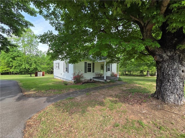 view of front facade featuring a porch, an outbuilding, a shed, and a front lawn