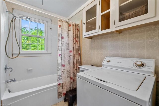 washroom featuring tile walls, cabinet space, and washer / clothes dryer