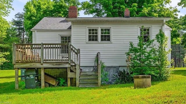 back of house featuring a lawn, a chimney, and a deck
