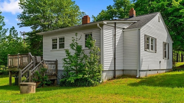 view of side of home with a lawn, a chimney, and a deck