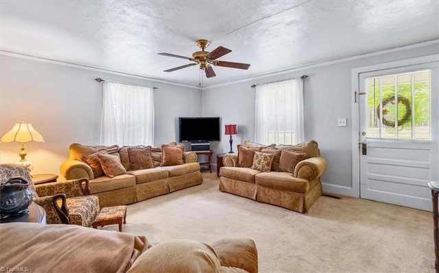 living area with crown molding, a ceiling fan, and light colored carpet