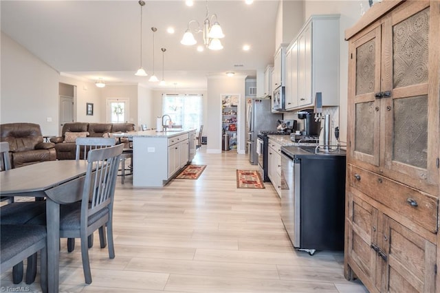 109 Red Maple Way, King, NC 27021 - kitchen with open floor plan, stainless steel appliances, a kitchen island with sink, light wood-style flooring, and hanging light fixtures