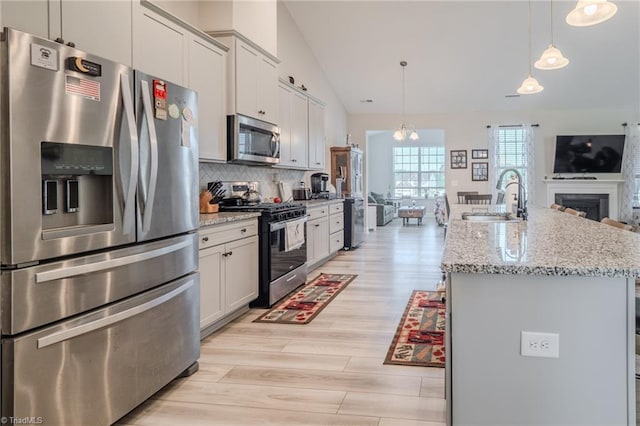 109 Red Maple Way, King, NC 27021 - kitchen with stainless steel appliances, a sink, light wood-style flooring, an island with sink, and decorative backsplash