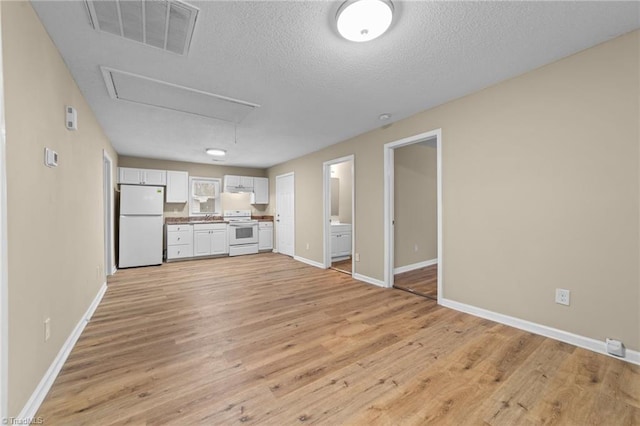 unfurnished living room featuring light hardwood / wood-style flooring and a textured ceiling