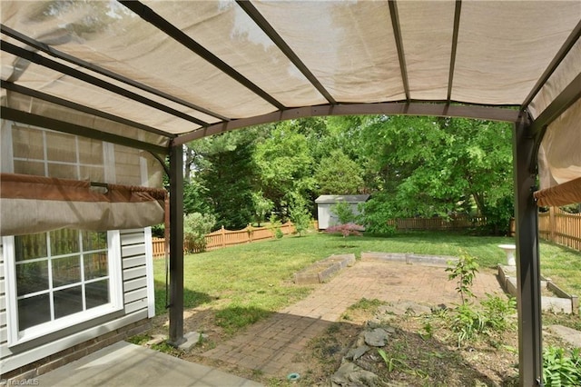 view of yard featuring a storage shed, an outbuilding, a fenced backyard, and a patio area