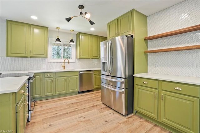 kitchen with light wood finished floors, tasteful backsplash, light countertops, stainless steel appliances, and a sink