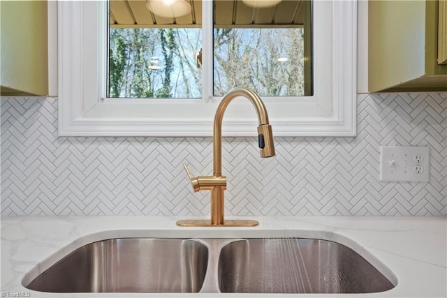 interior details featuring tasteful backsplash, light stone countertops, and a sink