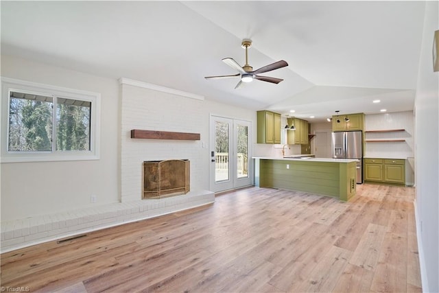 unfurnished living room with ceiling fan, visible vents, light wood-style flooring, and vaulted ceiling