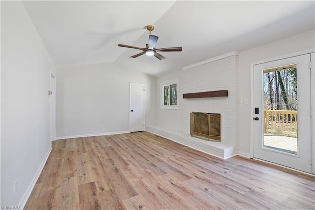 unfurnished living room featuring lofted ceiling, light wood finished floors, baseboards, a brick fireplace, and ceiling fan