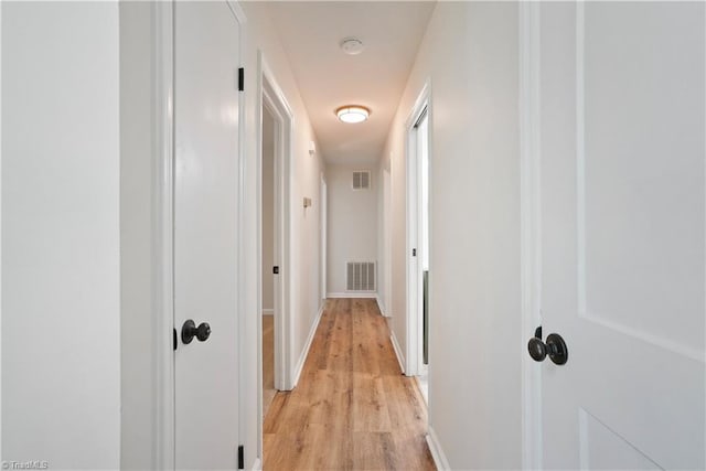 hall with light wood-style floors, visible vents, and baseboards