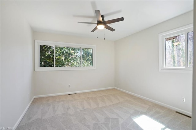 empty room featuring light carpet, visible vents, ceiling fan, and baseboards