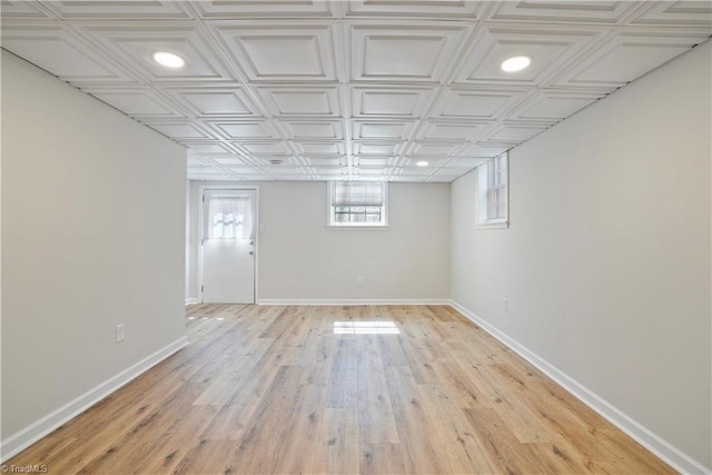 basement with light wood finished floors, an ornate ceiling, and baseboards