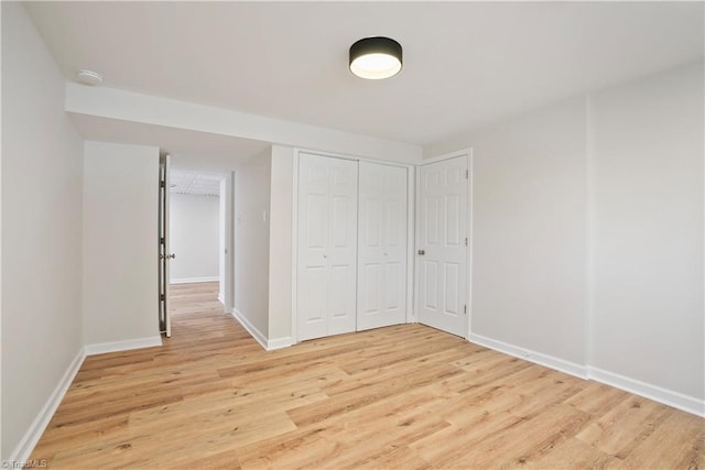 unfurnished bedroom featuring light wood-type flooring, baseboards, and a closet