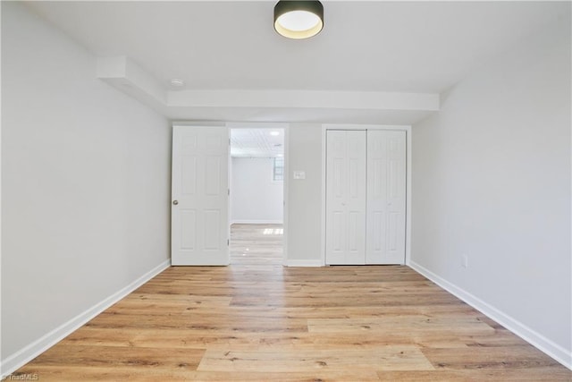 unfurnished bedroom with wood finished floors, baseboards, and a closet