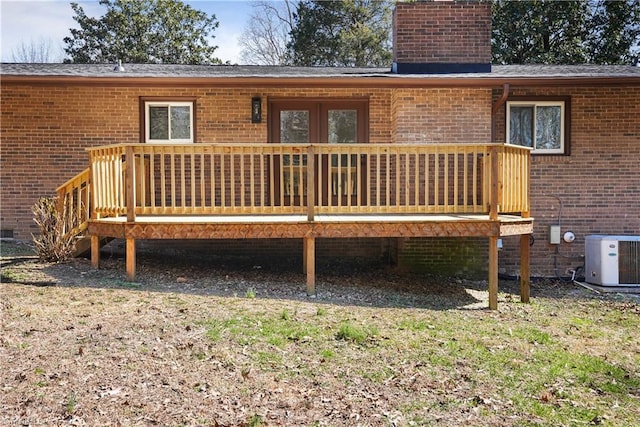 back of house featuring a wooden deck, central AC unit, brick siding, and a chimney