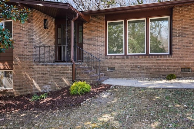 doorway to property featuring crawl space and brick siding