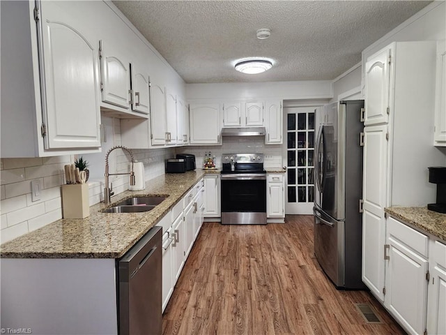6905 Harlow Dr, Archdale, NC 27263 - kitchen featuring stainless steel appliances, a sink, a textured ceiling, under cabinet range hood, and wood finished floors