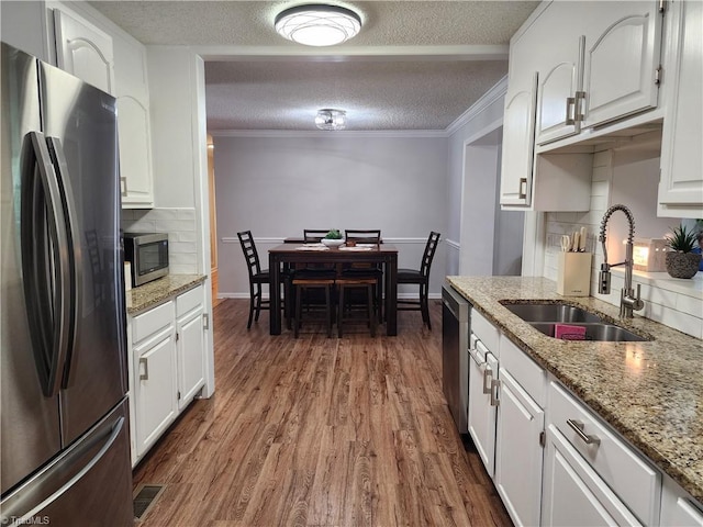 6905 Harlow Dr, Archdale, NC 27263 - kitchen with stainless steel appliances, a sink, wood finished floors, tasteful backsplash, and white cabinets