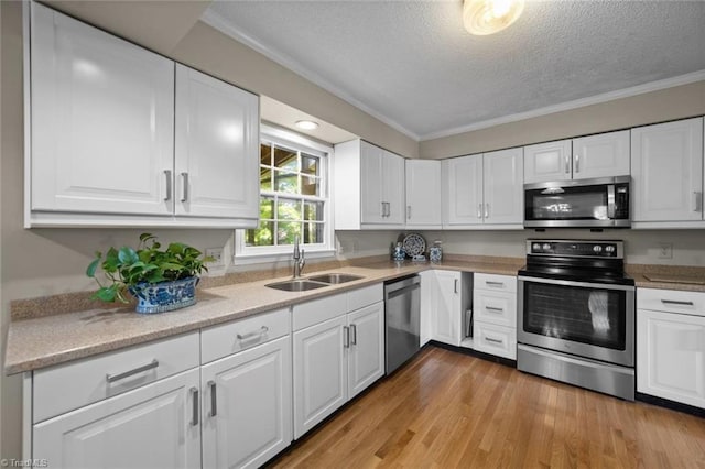 kitchen featuring crown molding, a textured ceiling, white cabinetry, a sink, and stainless steel appliances