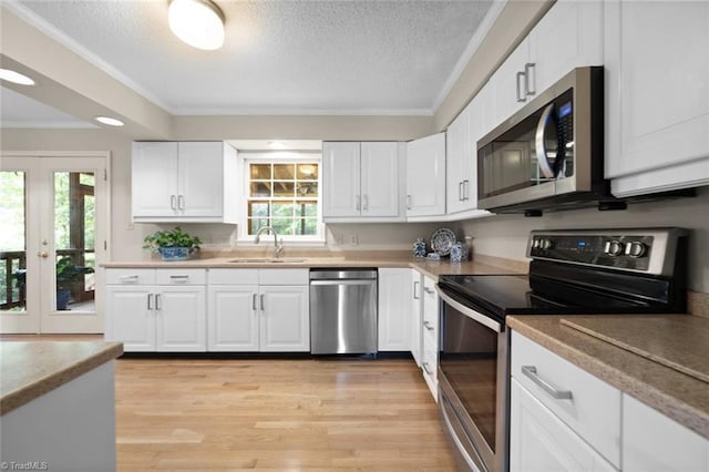 kitchen with ornamental molding, a textured ceiling, white cabinets, a sink, and stainless steel appliances
