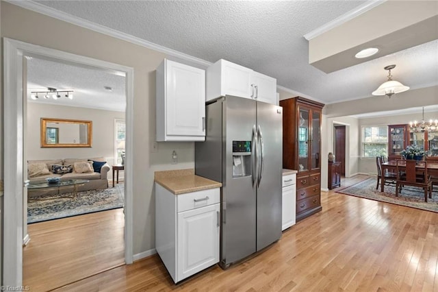 kitchen featuring ornamental molding, stainless steel fridge, a textured ceiling, white cabinetry, and light wood-style flooring