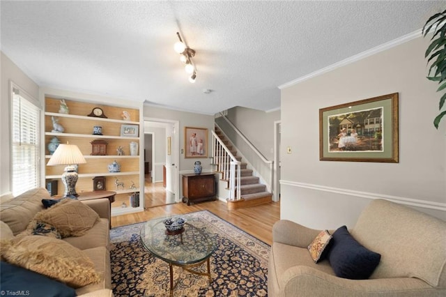 living area with stairs, a textured ceiling, ornamental molding, and light wood-style flooring