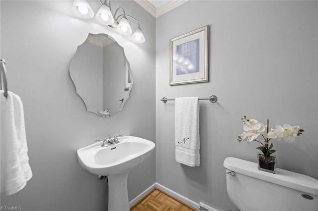 half bath featuring crown molding, baseboards, and toilet