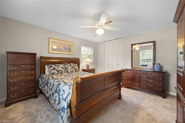 bedroom with baseboards, a ceiling fan, a closet, and light colored carpet