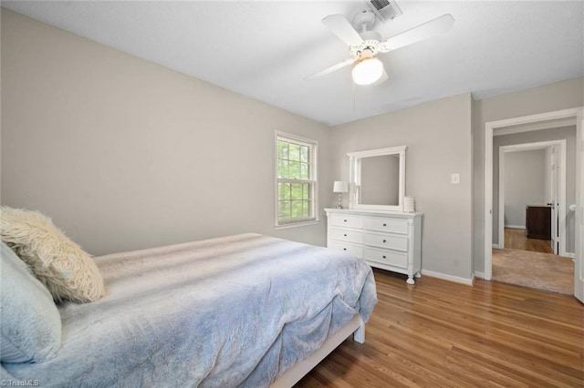bedroom with baseboards, ceiling fan, wood finished floors, and visible vents