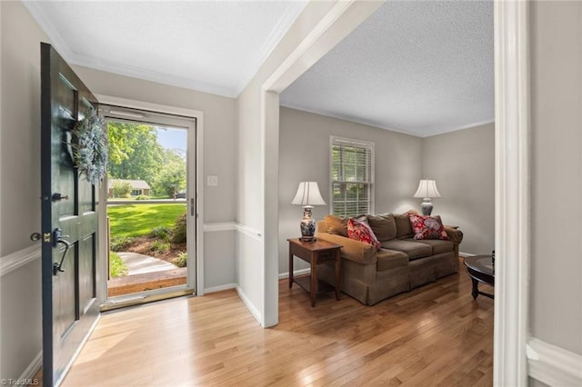 entrance foyer featuring crown molding, light wood-style flooring, and a healthy amount of sunlight