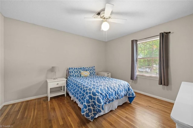 bedroom with baseboards, ceiling fan, and wood finished floors