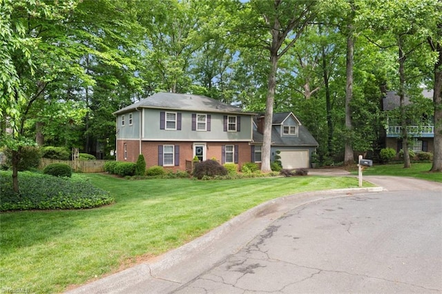 colonial inspired home featuring driveway, a front yard, a garage, brick siding, and fence