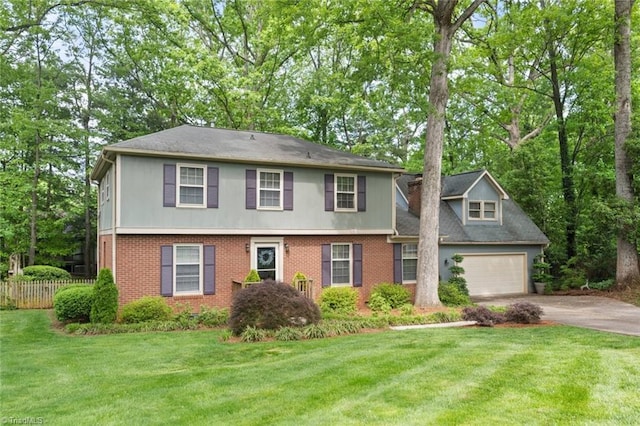colonial home with a garage, fence, a front yard, brick siding, and driveway