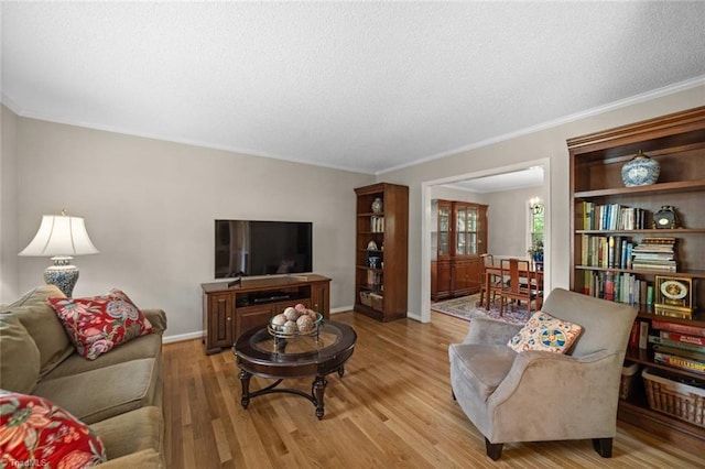 living room with a textured ceiling, ornamental molding, baseboards, and light wood finished floors
