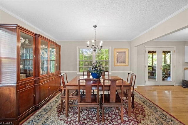 dining room with a healthy amount of sunlight, a textured ceiling, wood finished floors, and a notable chandelier