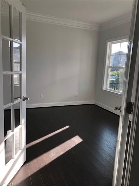 empty room featuring dark wood-type flooring, ornamental molding, and french doors